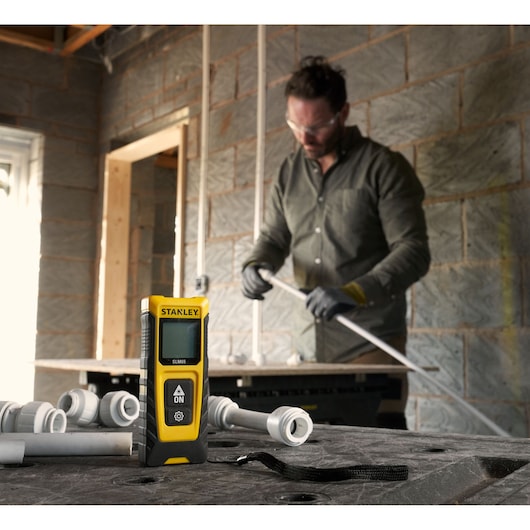 STANLEY STHT77065-0 télémètre laser dans un atelier avec des tuyaux et raccords.