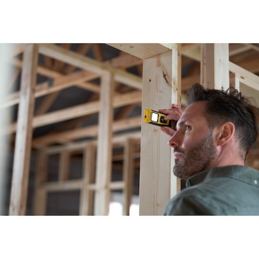 STANLEY STHT77065-0 télémètre laser numérique utilisé sur une charpente en bois sur chantier.