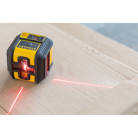 Foto van STANLEY STHT77502-1 laserwaterpas die rode lijnen op karton projecteert.