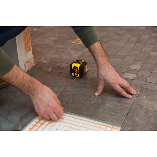 STANLEY STHT77502-1 laserwaterpas voor nauwkeurige tegeluitlijning op bruine tegelvloer.