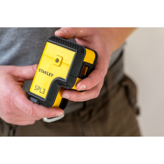 Foto van STANLEY SPL3 STHT77503-1 geel-zwarte laserwaterpas vastgehouden in hand, voorkant.