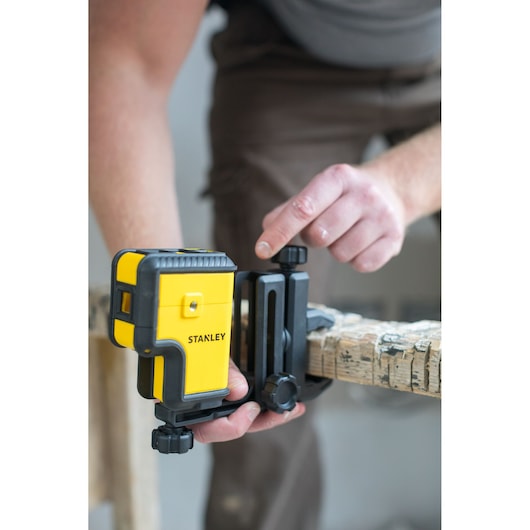 STANLEY STHT77503-1 laserwaterpas op houten balk, gebruiker stelt montagebeugel af.