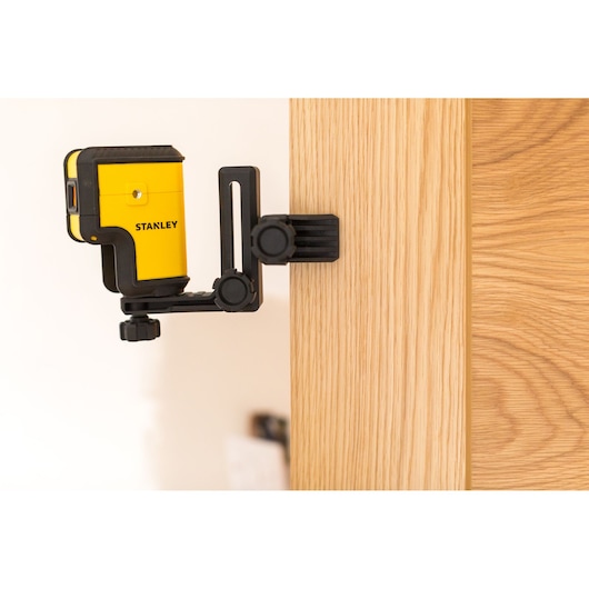 STANLEY STHT77503-1 gele laserwaterpas gemonteerd op zwarte klem aan houten oppervlak.