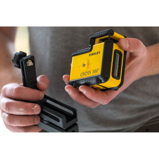 Foto van STANLEY STHT77504-1 CROSS 360 laserwaterpas met montagesteun, vastgehouden in handen.
