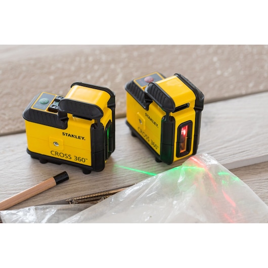 Foto van STANLEY STHT77504-1 CROSS 360 laserwaterpas, twee units op houten oppervlak met groene en rode laserlijnen.