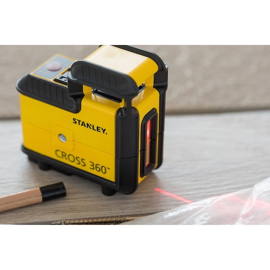 STANLEY STHT77504-1 Cross 360™ gele laserwaterpas op tafel, zijaanzicht, rode straal zichtbaar.