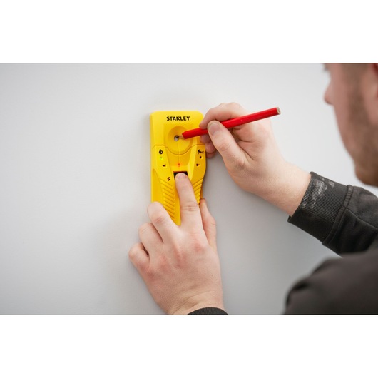 STANLEY STHT77587-0 gele balkzoeker tegen muur, gebruiker markeert plek met rode potlood.