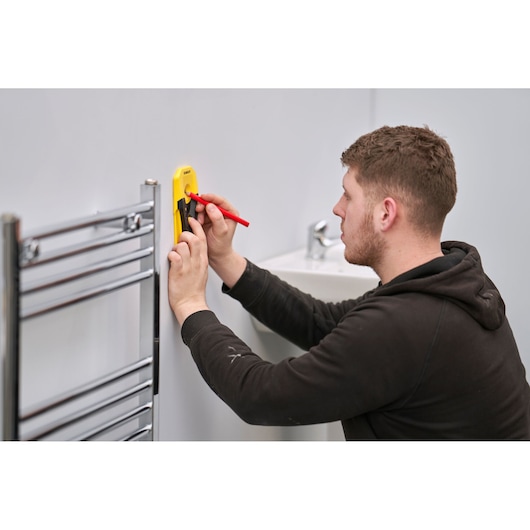 STANLEY STHT77588-0 wandmarkeer gereedschap gebruikt door persoon bij wastafel en chromen handdoekrek.