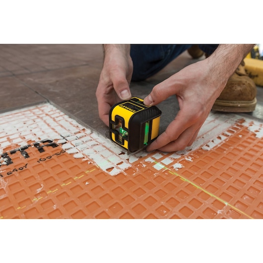 Foto van een STANLEY STHT77592-1 laserwaterpas op een oranje tegelmat.
