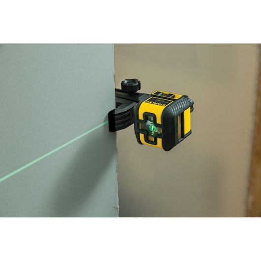 STANLEY STHT77592-1 laser niveau gereedschap met groene lijn op de muur, vastgezet met klem.