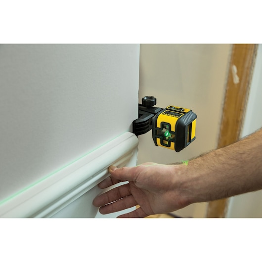 STANLEY STHT77592-1 laserwaterpas gereedschap projecteert groene lijn op muur bij plintinstallatie.