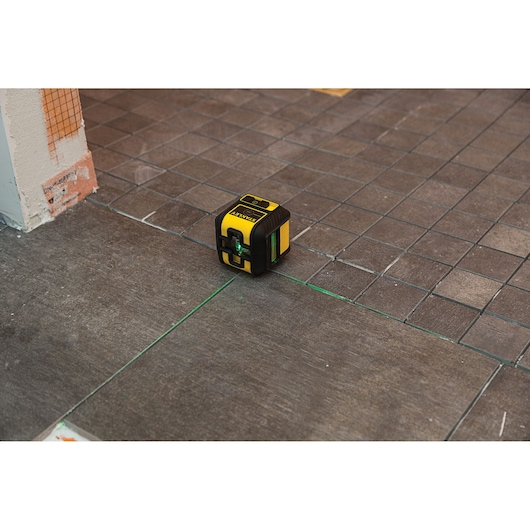 STANLEY STHT77592-1 laserwaterpas projecteert groene lijnen op tegelvloer.