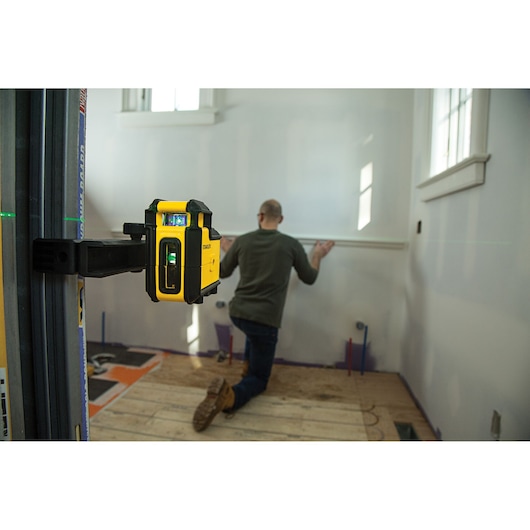 STANLEY STHT77594-1 laserwaterpas in gebruik, aan de muur gemonteerd, vakman lijnt wandlijst uit.