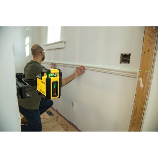Foto van STANLEY STHT77594-1 laserwaterpas gemonteerd, projecteert groene lijn voor wandafwerking.