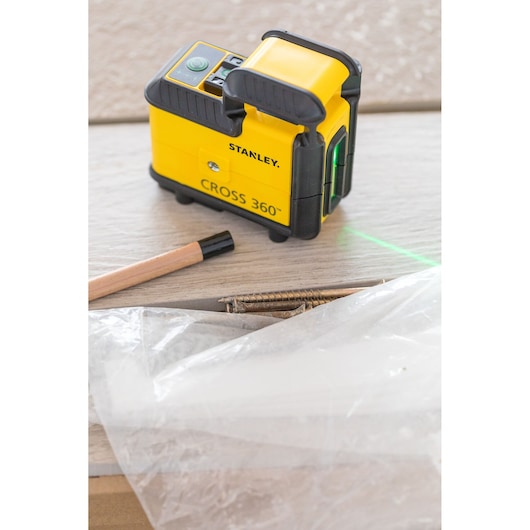 STANLEY STHT77594-1 laserwaterpas CROSS 360 op houten oppervlak met potlood, schroeven en plastic folie.