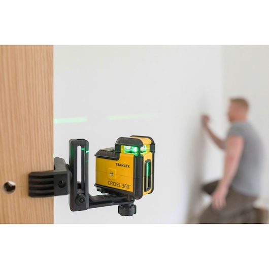 STANLEY STHT77594-1 CROSS 360° laserwaterpas op klem gemonteerd, groene lijnen projecterend in werkruimte.