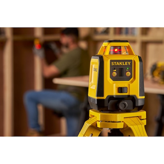 Photographie du niveau laser STANLEY STHT77616-0 sur trépied, utilisé dans un atelier.