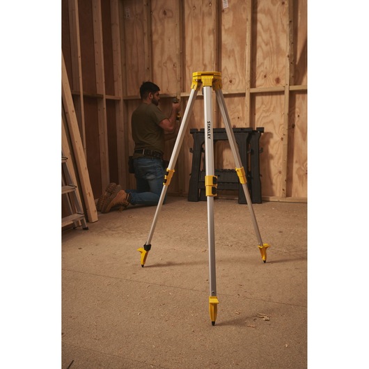 STANLEY STHT77625-1 statief met gele accenten, neergezet in een houten constructieruimte.