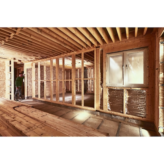 STANLEY STHT77666-0 photographie d'une maison à ossature bois en construction avec poutres apparentes et fenêtre.