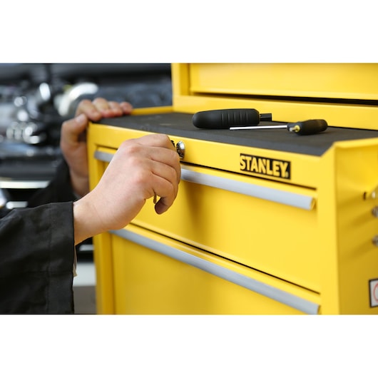 Photo du tiroir de coffre à outils jaune STANLEY STMT1-75063 verrouillé à la main, outils dessus.