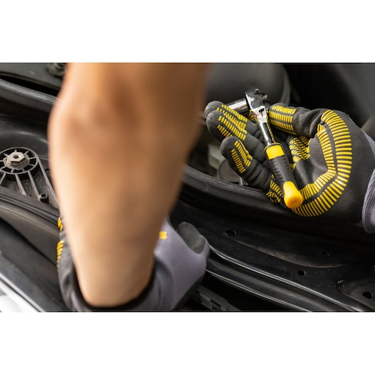 STANLEY STMT82663-0 ratelsleutel vastgehouden in gehandschoende hand, close-up, auto reparatie context.