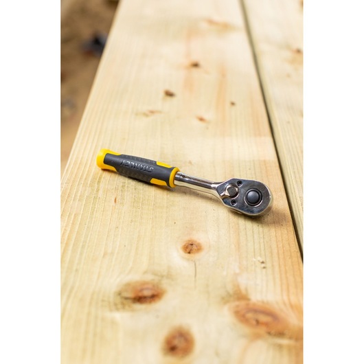 STANLEY STMT82663-0 ratelsleutel met geel-zwart handvat op houten oppervlak.