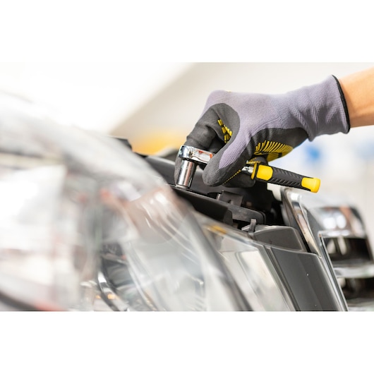 STANLEY STMT82663-0 ratel gebruikt op autokoplamp, close-up van grip en gereedschap.