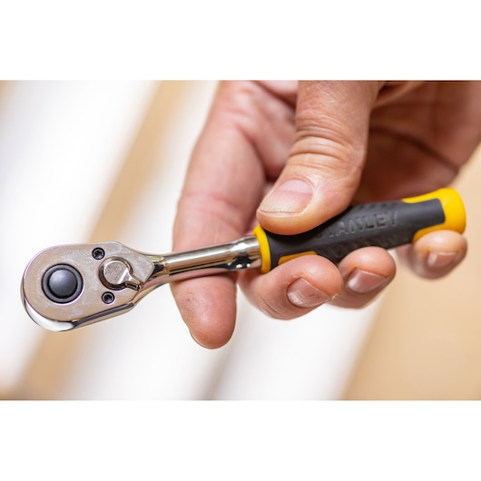 STANLEY STMT82663-0 ratelsleutel met zwart-gele handgreep, close-up in hand vastgehouden.