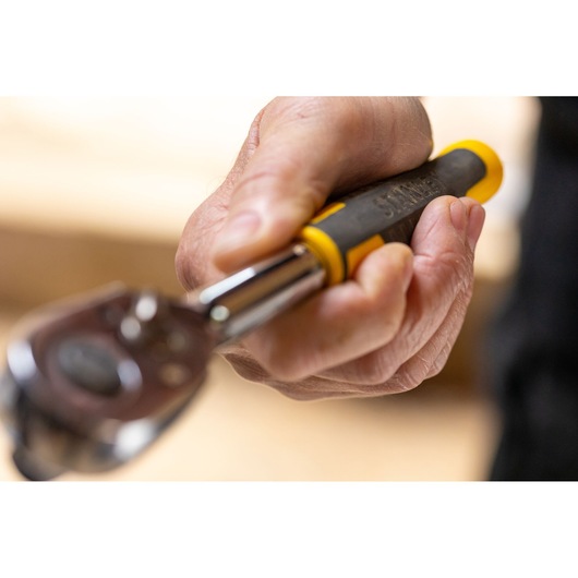 Clé à cliquet STANLEY STMT82664-0 avec poignée noire et jaune, tenue en main, vue rapprochée.