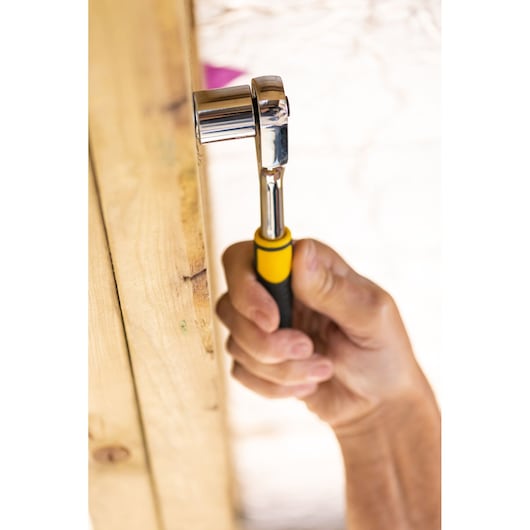 Clé à cliquet STANLEY STMT82664-0 avec poignée jaune et noire en utilisation, vue rapprochée.