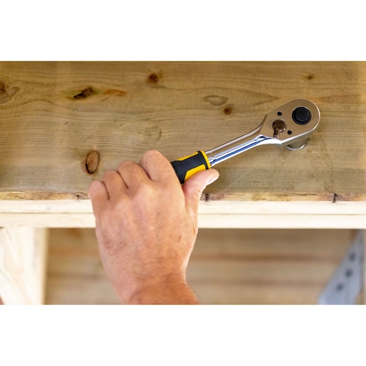 STANLEY STMT82665-0 ratelsleutel gebruikt op hout, close-up van een hand met het gereedschap.
