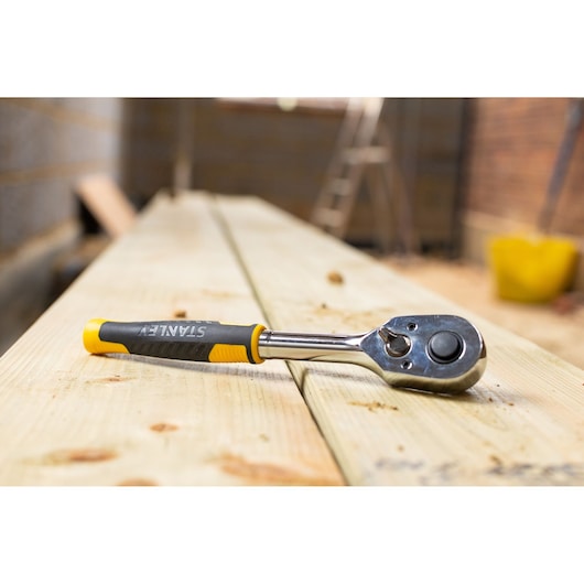 STANLEY STMT82665-0 ratelsleutel met zwart-geel handvat op houten planken, schuinaanzicht.
