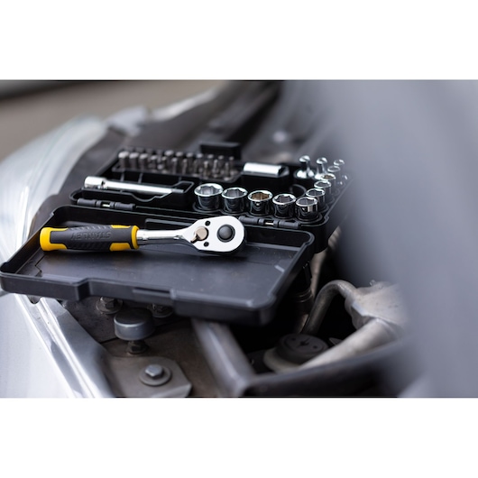 STANLEY STMT82672-0 ratel en doppenset op zwart dienblad, getoond in auto-reparatieomgeving.