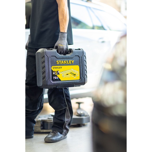 STANLEY STMT82828-1 dopsleutelset koffer vastgehouden door persoon met handschoenen in garage.