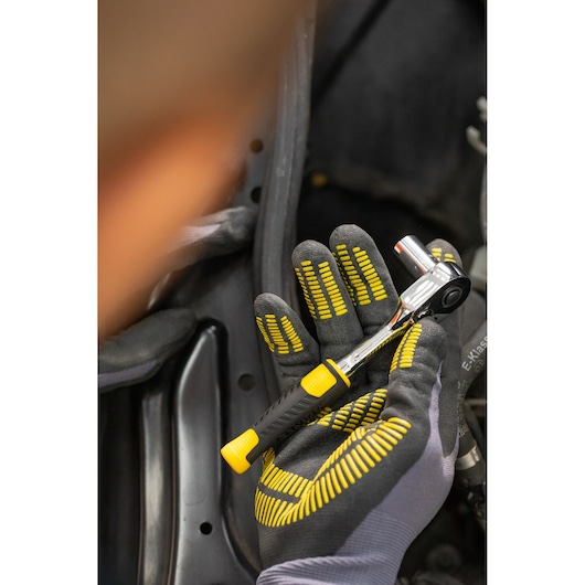 STANLEY STMT82828-1 ratelsleutel met zwart-geel handvat, vastgehouden in gehandschoende hand, close-up.