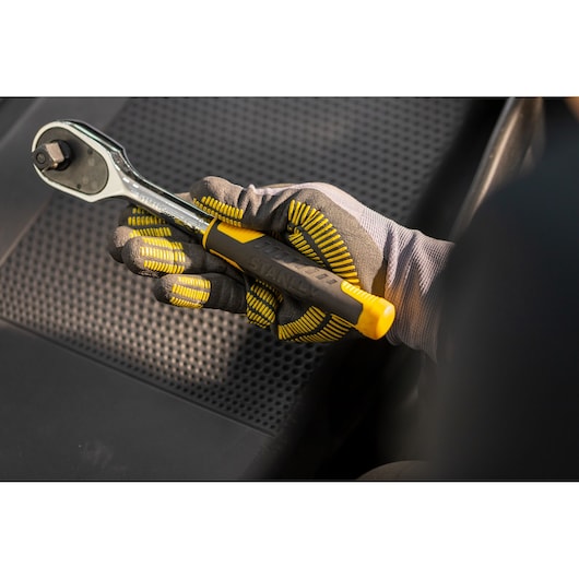 STANLEY STMT82830-1 ratelsleutel met geel-zwart handvat in een gehandschoende hand, close-upfotografie.