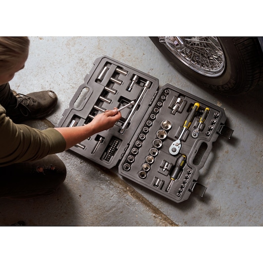 STANLEY STMT82831-1 ratel- en doppenset met 72 stuks in zwarte koffer, open op garagevloer naast auto.