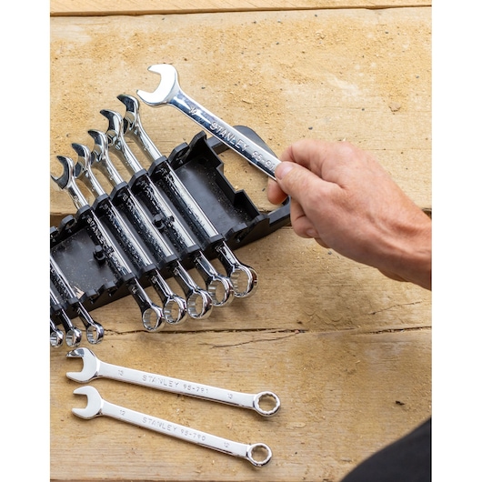 Jeu de clés STANLEY STMT82842-0 dans un support noir, main tenant une clé chromée, deux clés sur une surface en bois.