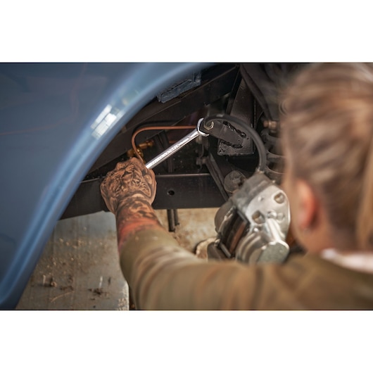 STANLEY STMT82846-0 platte ratelsleutel gebruikt op autoremleiding, getatoeëerde arm zichtbaar.