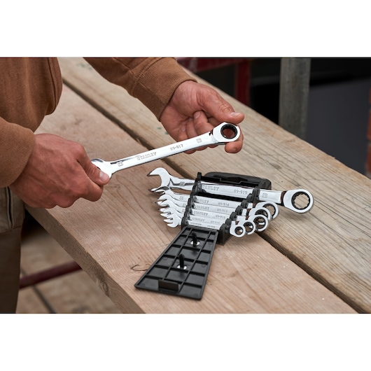 STANLEY STMT82846-0 7-delige platte ratelsleutelset met koffer op werkbank, hand houdt een sleutel vast.