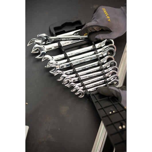 STANLEY STMT82847-0 jeu de clés à cliquet avec support, finition chromée, mains gantées sur surface noire.