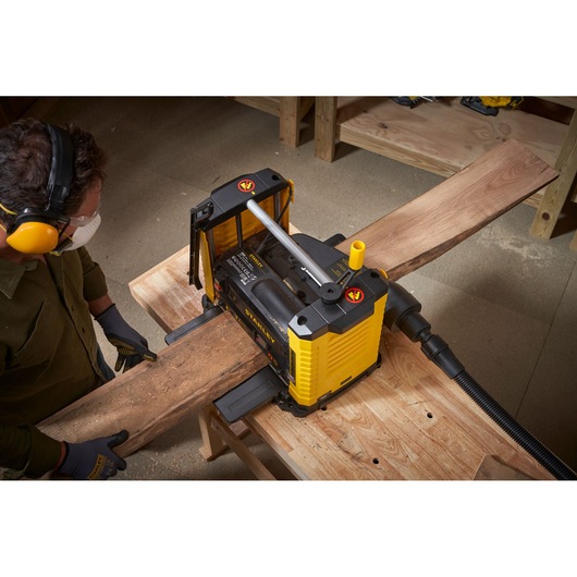Foto van STANLEY STP18-B2 schaafmachine in gebruik, gladstrijken van een houten plank in een werkplaats, bovenaanzicht.