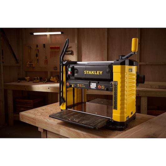 STANLEY STP18-B2 raboteuse, jaune et noire, photographie dans un atelier sur une table en bois.