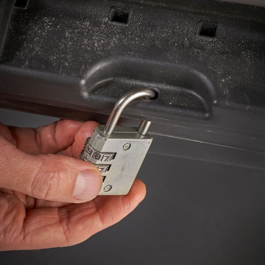 Foto van STANLEY STST1-70715 opbergbox met een hand die een cijferhangslot op de voorkant bevestigt.