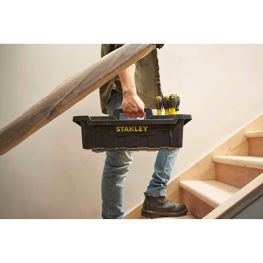 Stanley STST1-72359 zwarte gereedschapskist met schroevendraaiers, gedragen door persoon op trap.