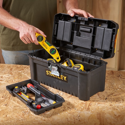 STANLEY STST1-75518-KR boîte à outils noire avec outils, couvercle ouvert, photographiée sur un établi.