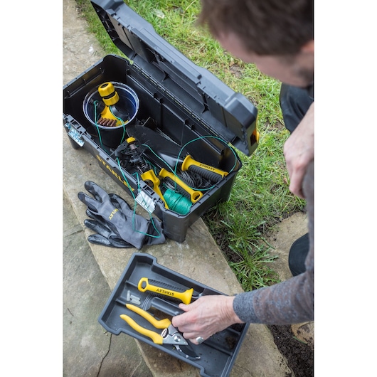 STANLEY STST1-75521 gereedschapskist met open deksel, met tuingereedschap en handschoenen, bovenzicht buiten.