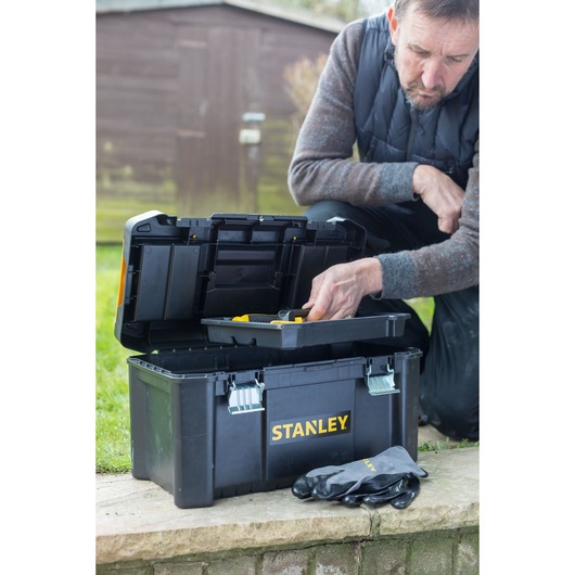 Foto van de STANLEY STST1-75521 gereedschapskist buiten, deksel open met bak zichtbaar, handschoenen ervoor.
