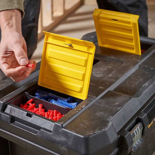 Photo de la boîte à outils STANLEY STST1-80150 avec compartiments à couvercle jaune contenant des chevilles rouges et bleues.