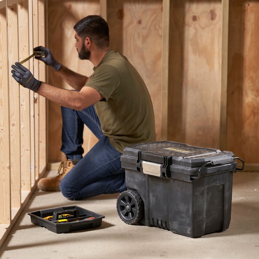 STANLEY STST33090-1 gereedschapskist op wielen in werkplaats met lade en gebruiker die houten balken meet